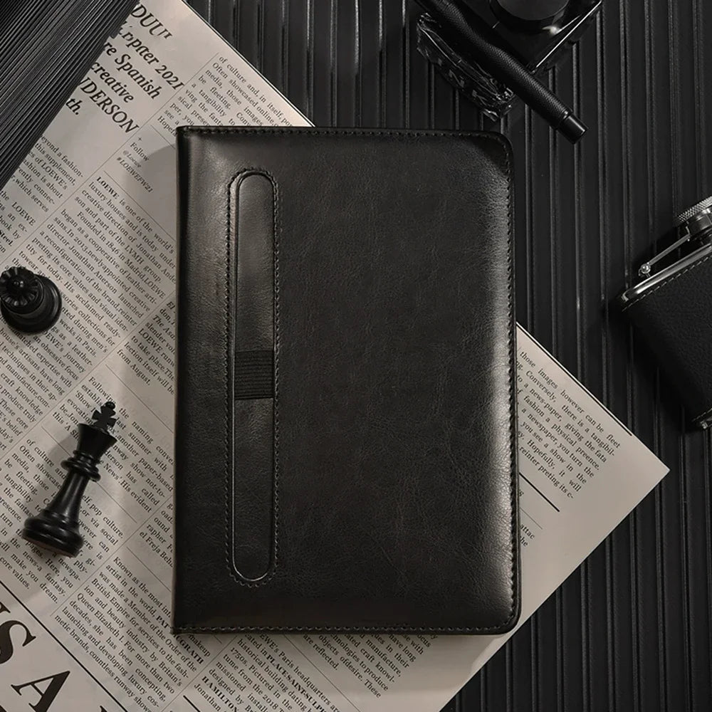 Black leather notebook on a newspaper with a pen and chess piece