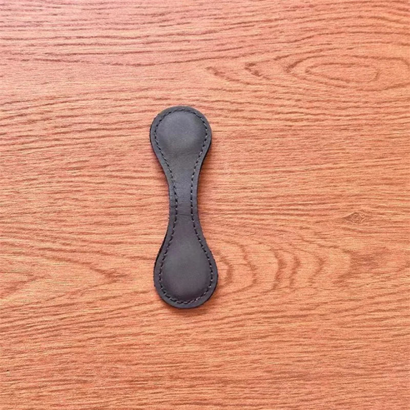 Black leather strap end on a wooden surface