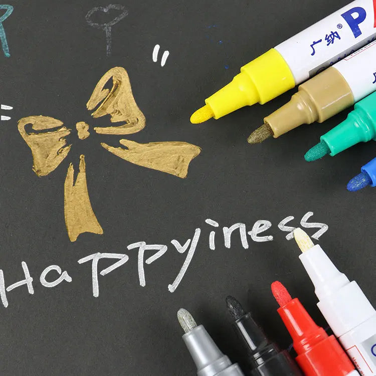Colorful markers on a blackboard with a gold bow and the word 'Happiness'.