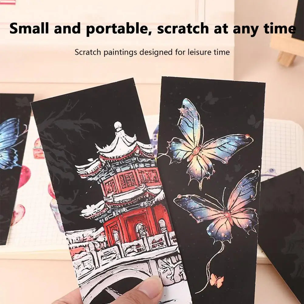Scratch art cards with a pagoda and butterfly design, held by a hand.