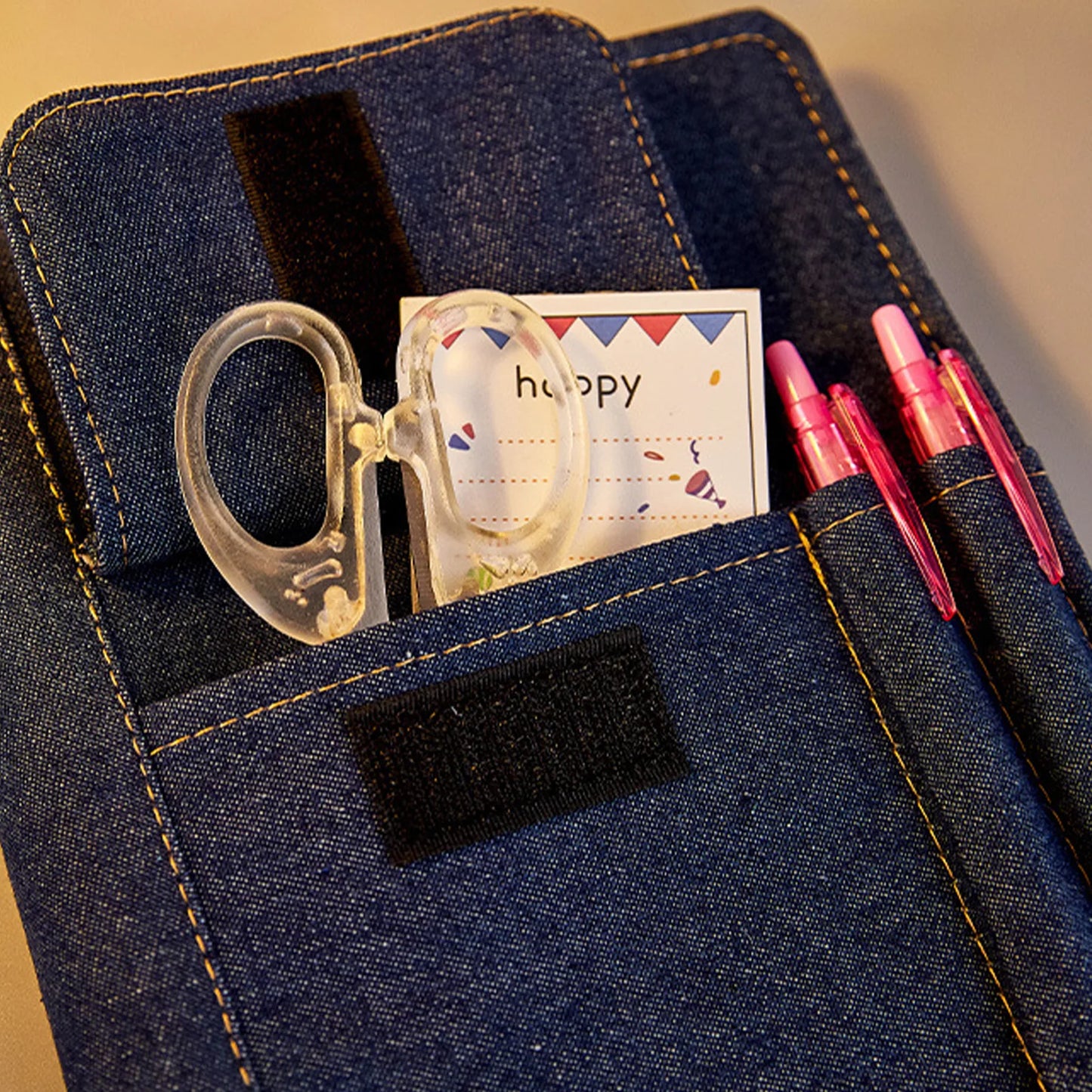 Denim pocket with a clear plastic item, card, and pens.