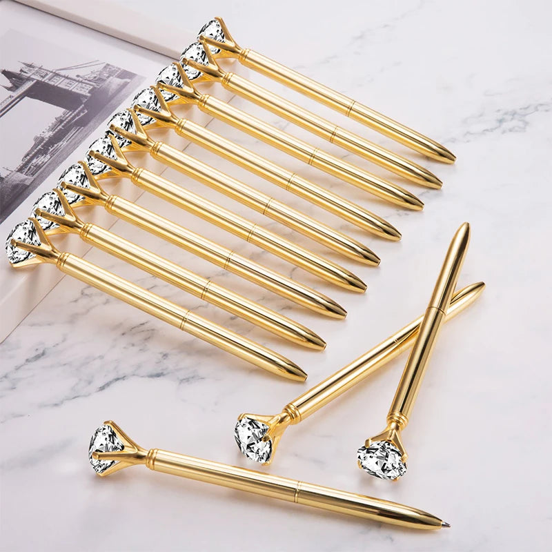 Gold pens with diamond gemstone accents on a marble surface