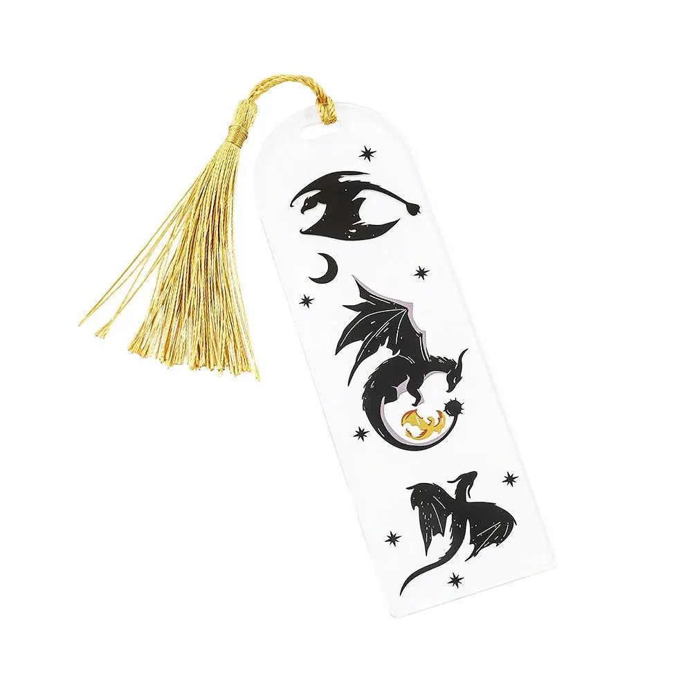 Decorative bookmark with tassel featuring black dragon and witch hat designs on a white background