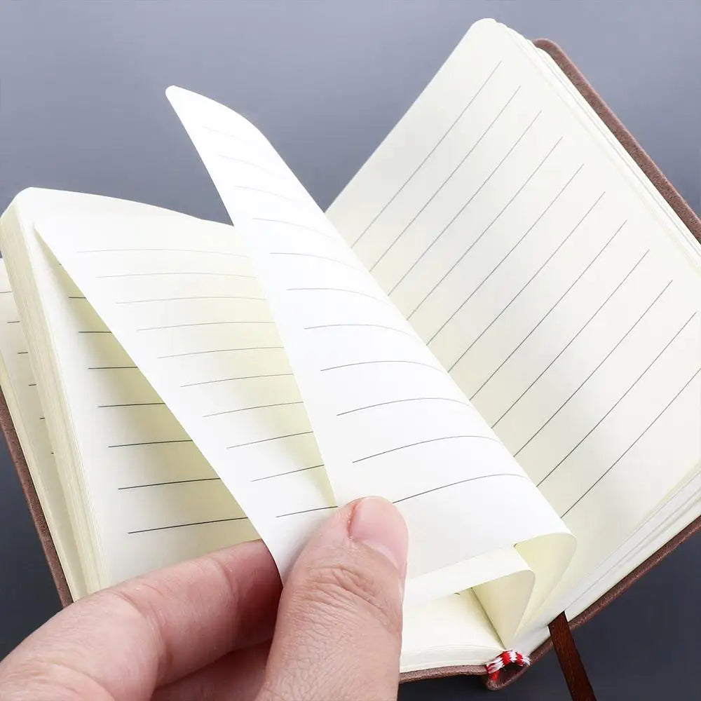 Hand holding a stack of lined paper over an open notebook with a gray background