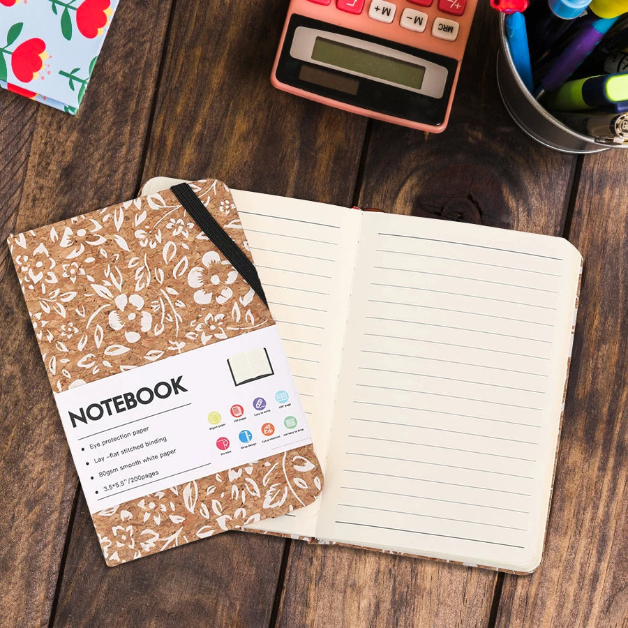 Floral notebook on a wooden surface with stationery items