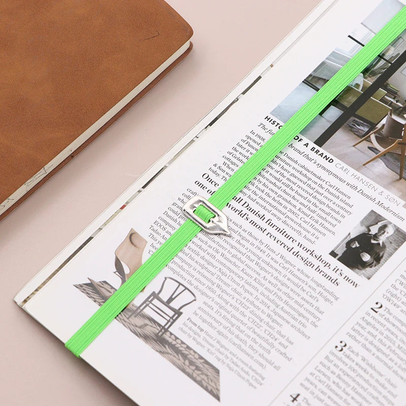 Open magazine with a green ribbon bookmark on a beige surface