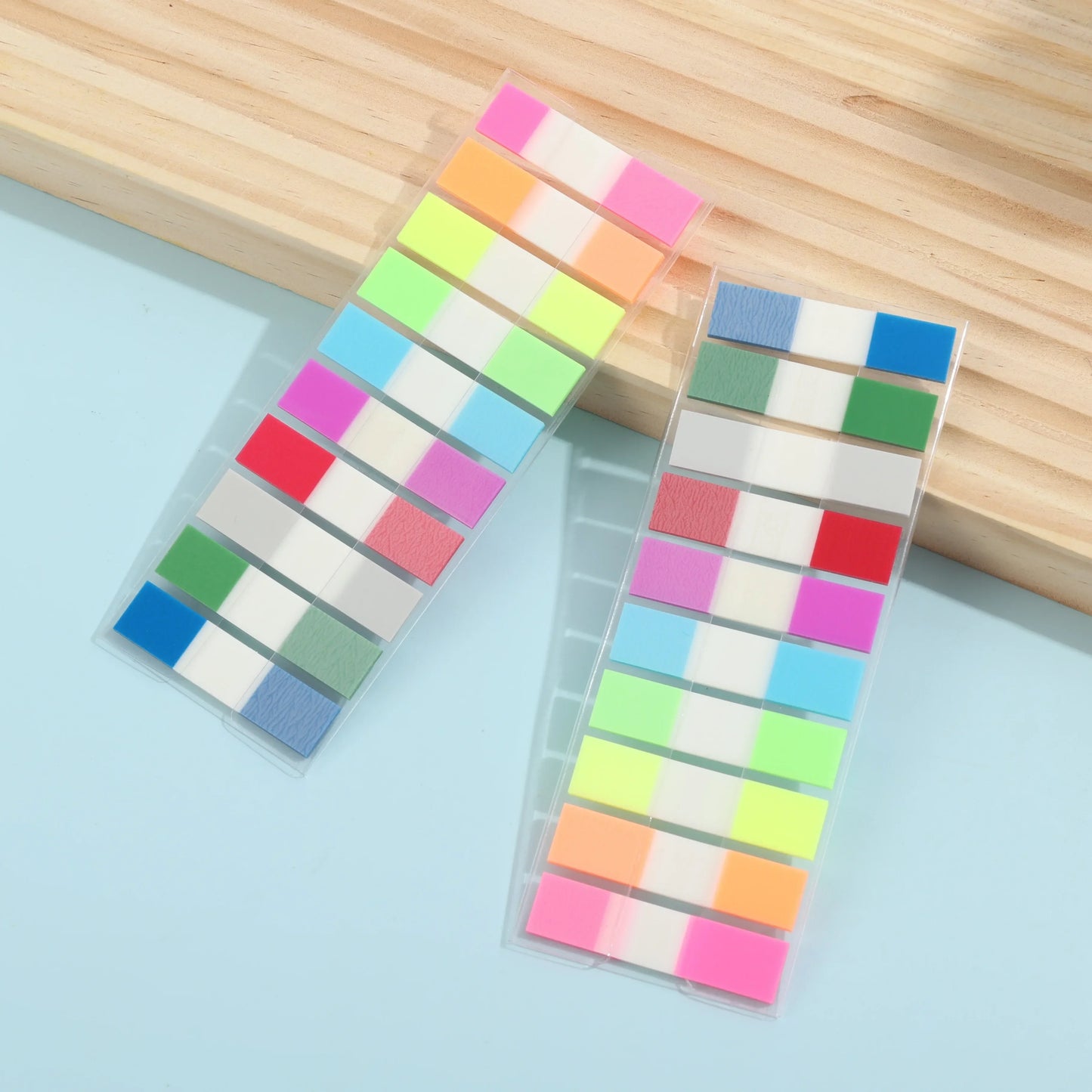 Colorful square stickers in clear plastic packaging on a light blue surface with wooden background