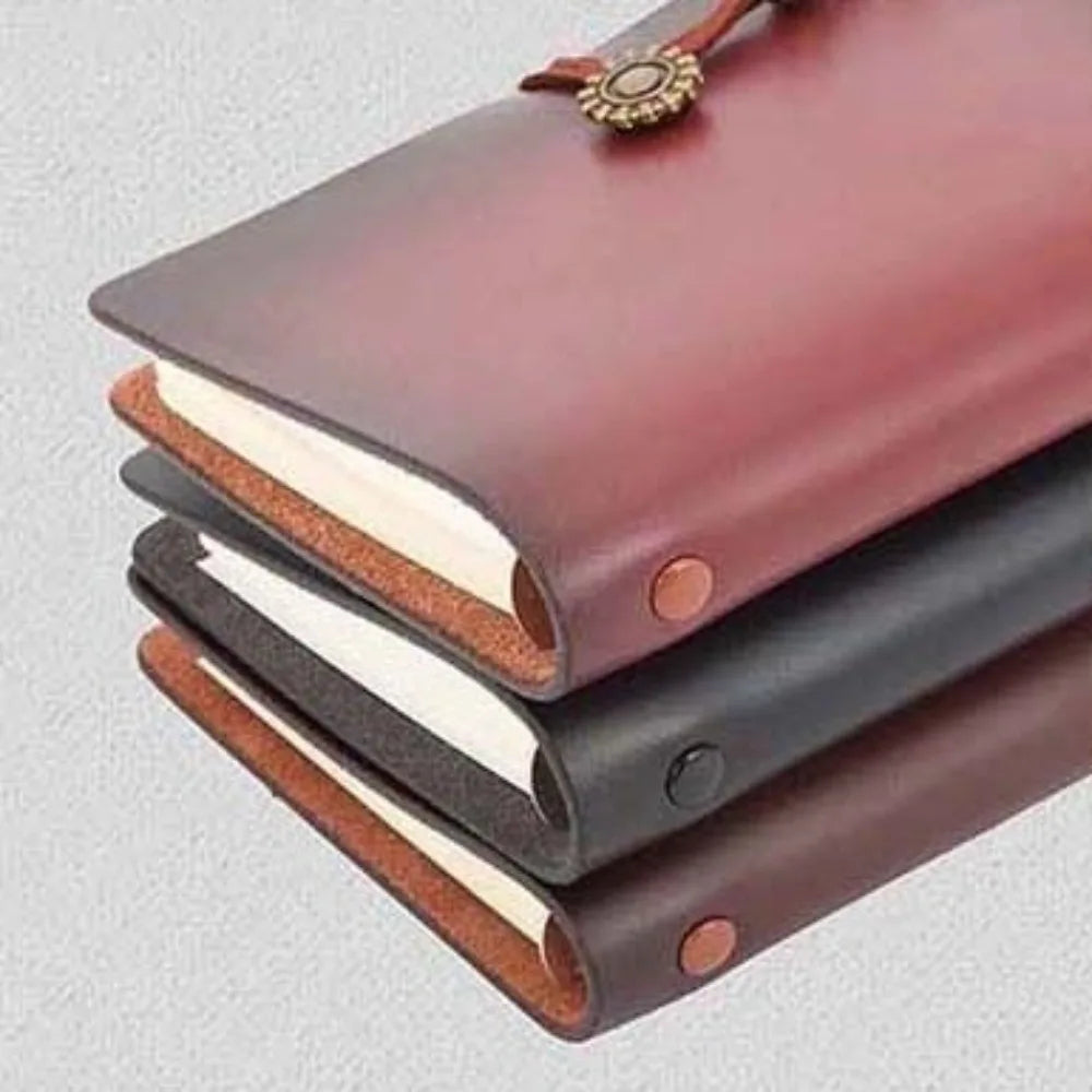 Three leather-bound notebooks stacked on a light gray background