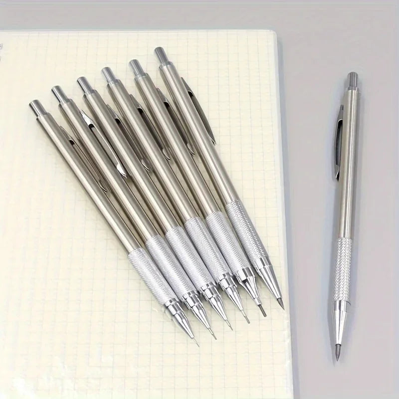 Set of silver pens on a notebook with one pen standing upright.