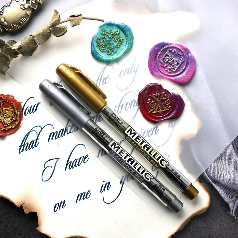 Metallic markers on a surface with decorative wax seals and calligraphy.