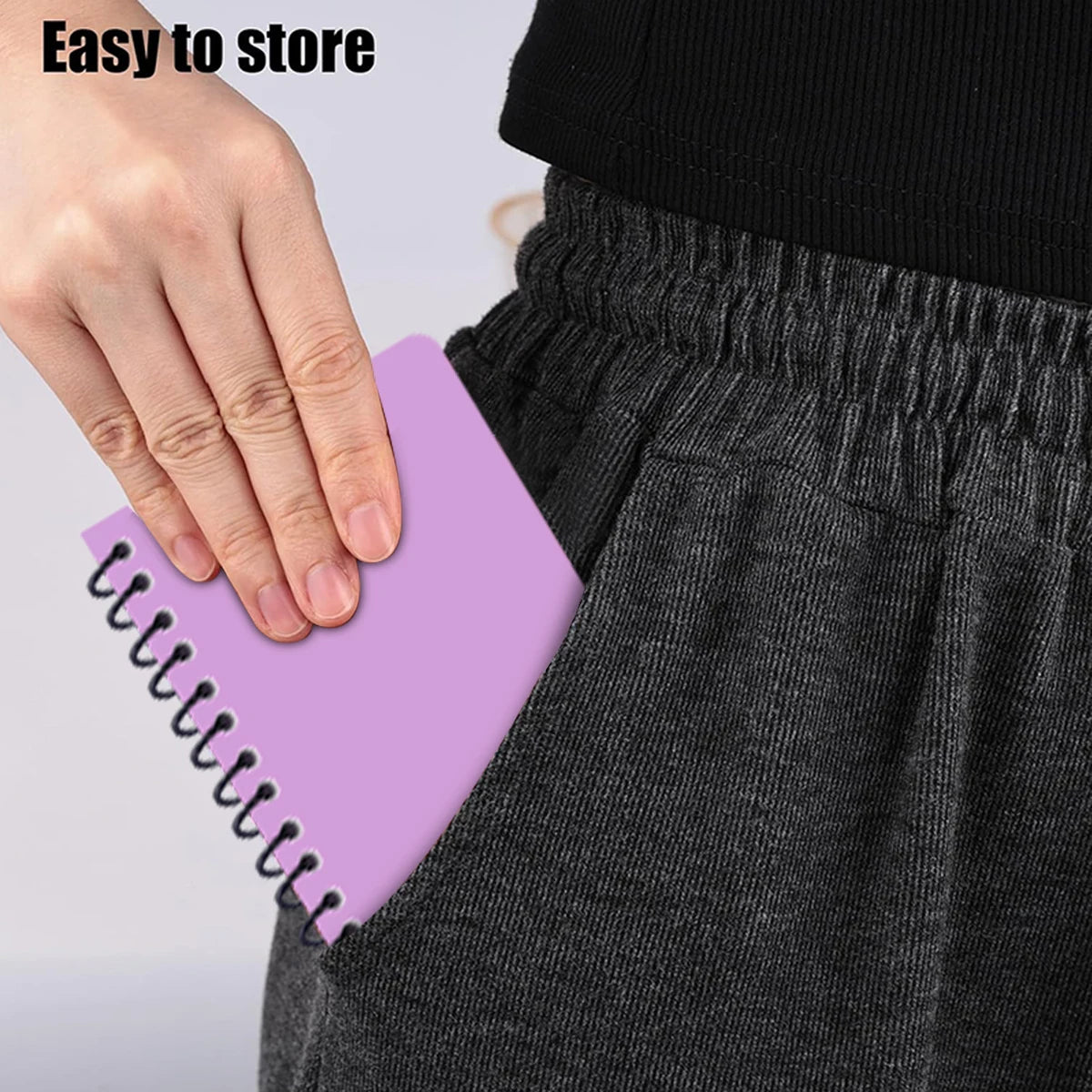 Person holding a purple notebook with a spiral binding against a plain background