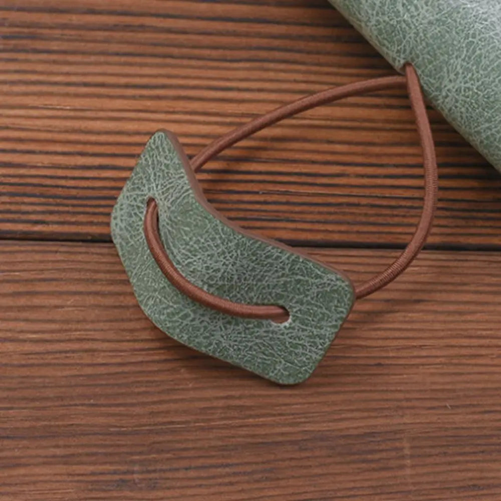 Green leather patch with brown strap on a wooden surface