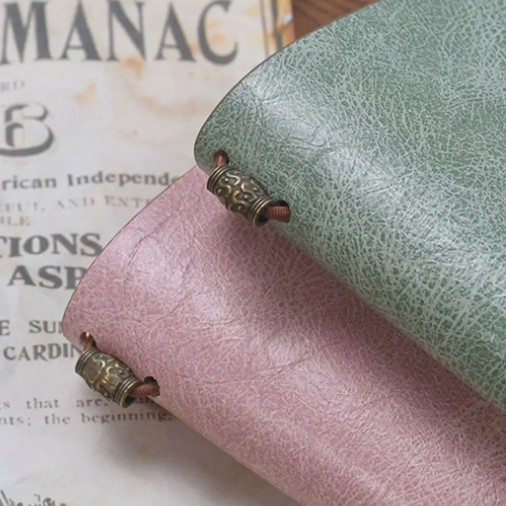 Close-up of pink and green leather-bound books with decorative clasps on an old newspaper background.