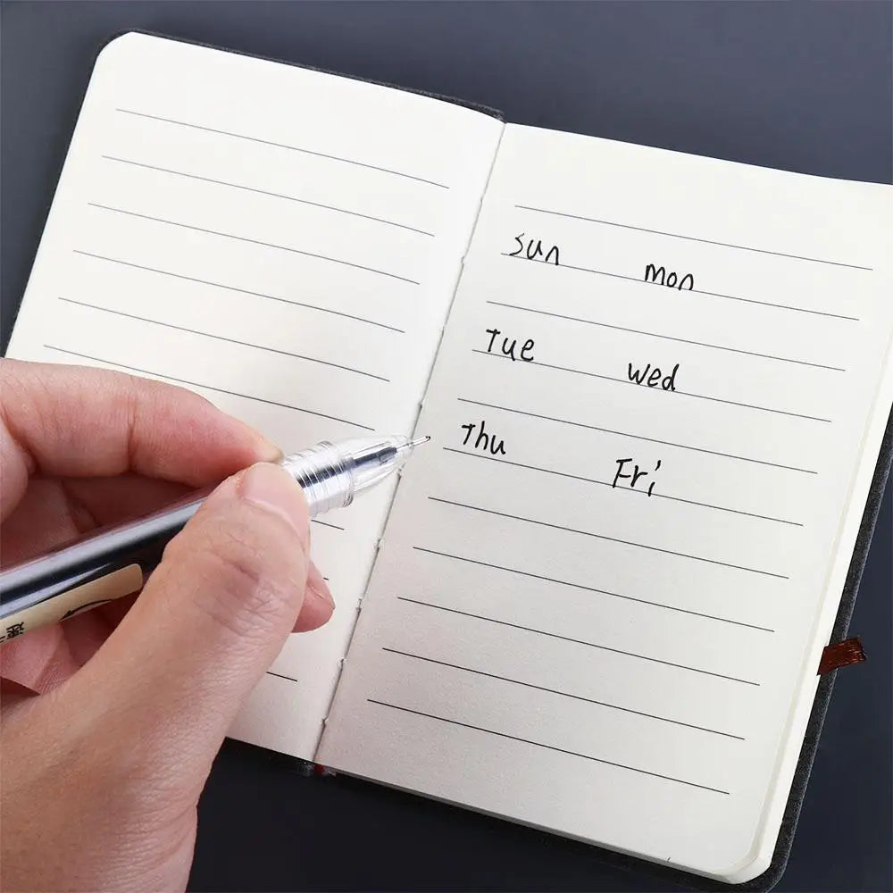 Hand writing in a small notebook with a pen on a dark background
