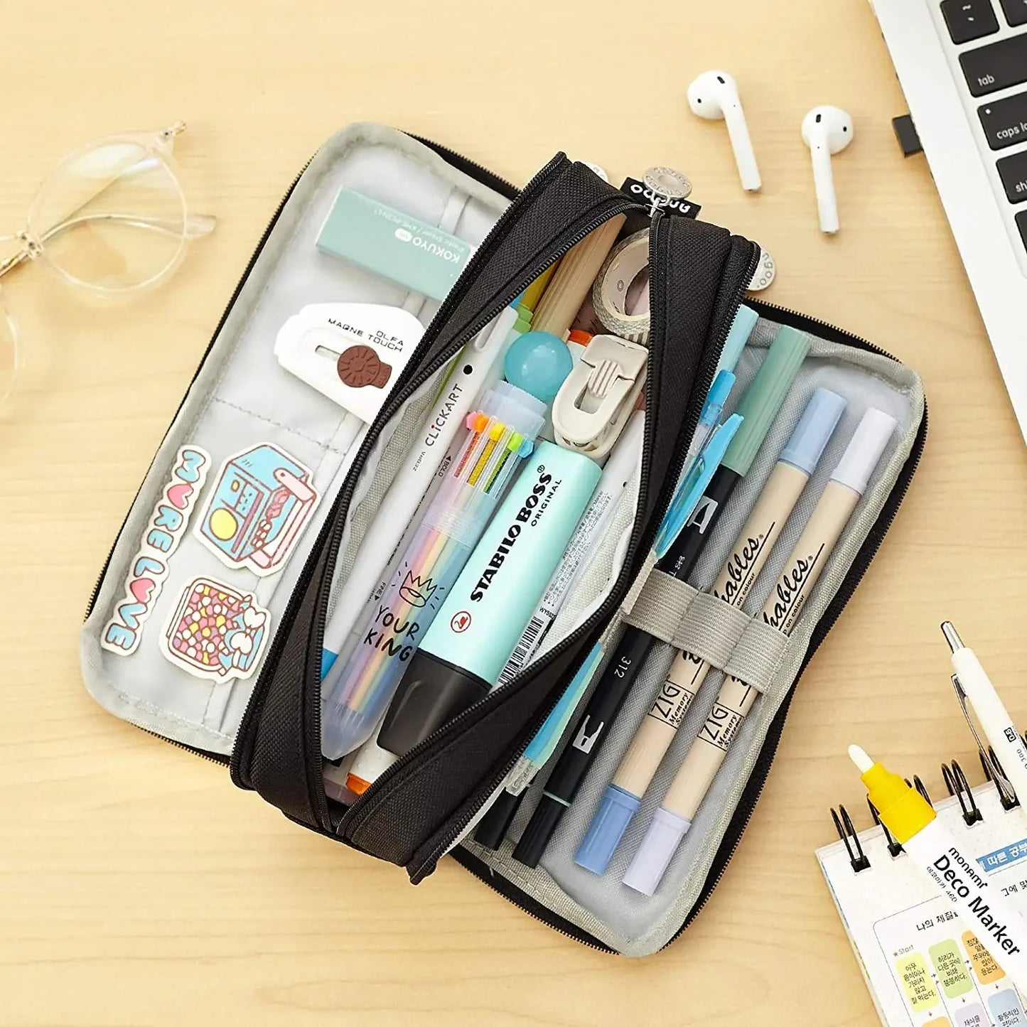 Pencil case with stationery items on a wooden surface