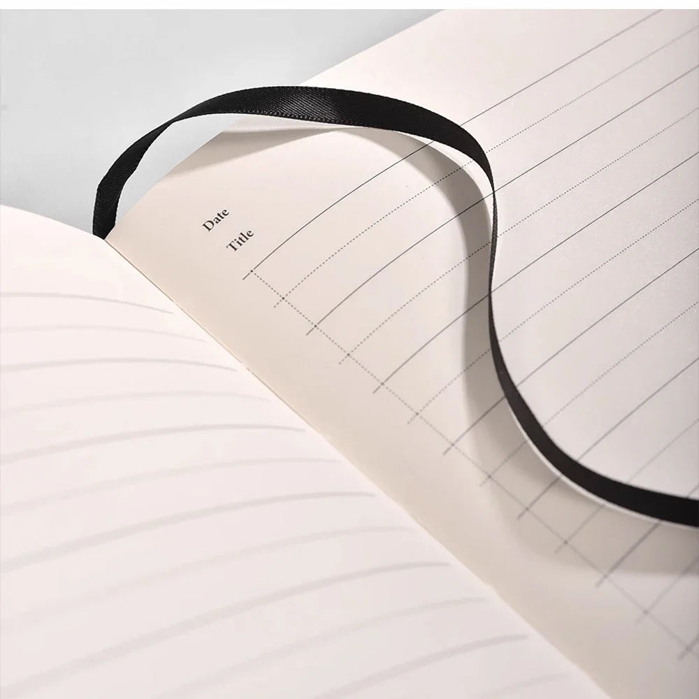 Notebook with a black ribbon bookmark on a light gray background