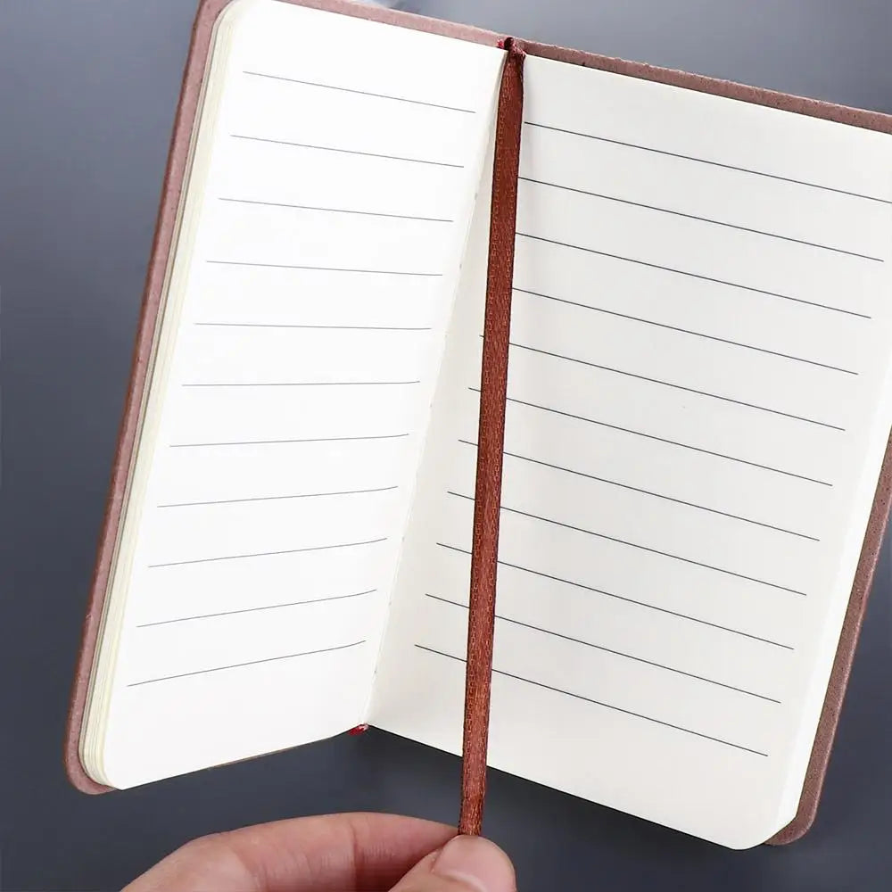 Open notebook with lined pages held by a hand against a dark background