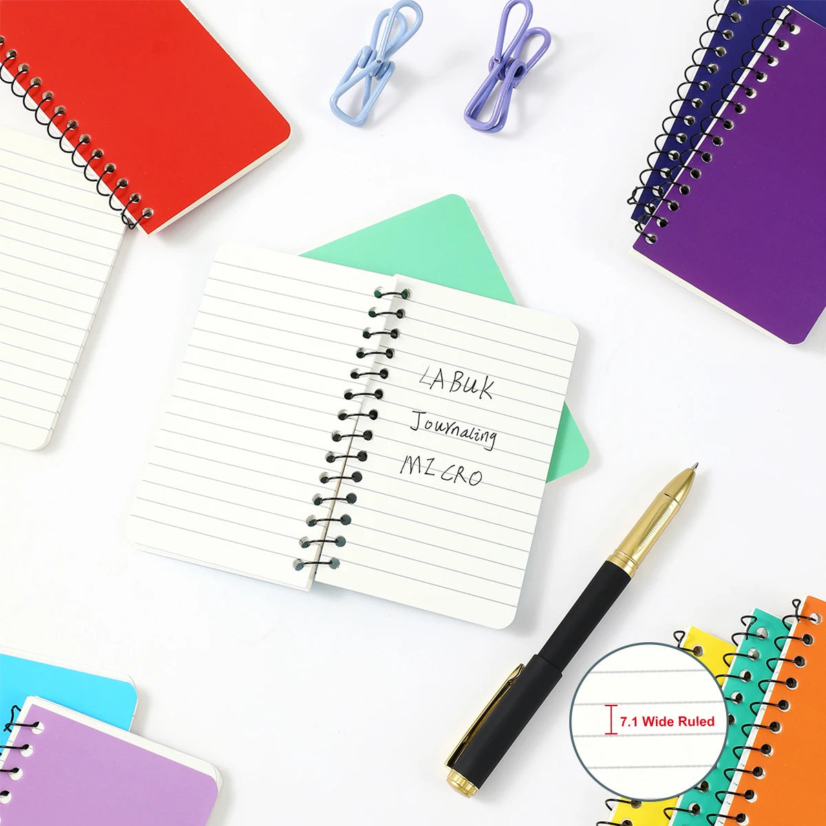 Colorful notebooks, a pen, and clips on a white background