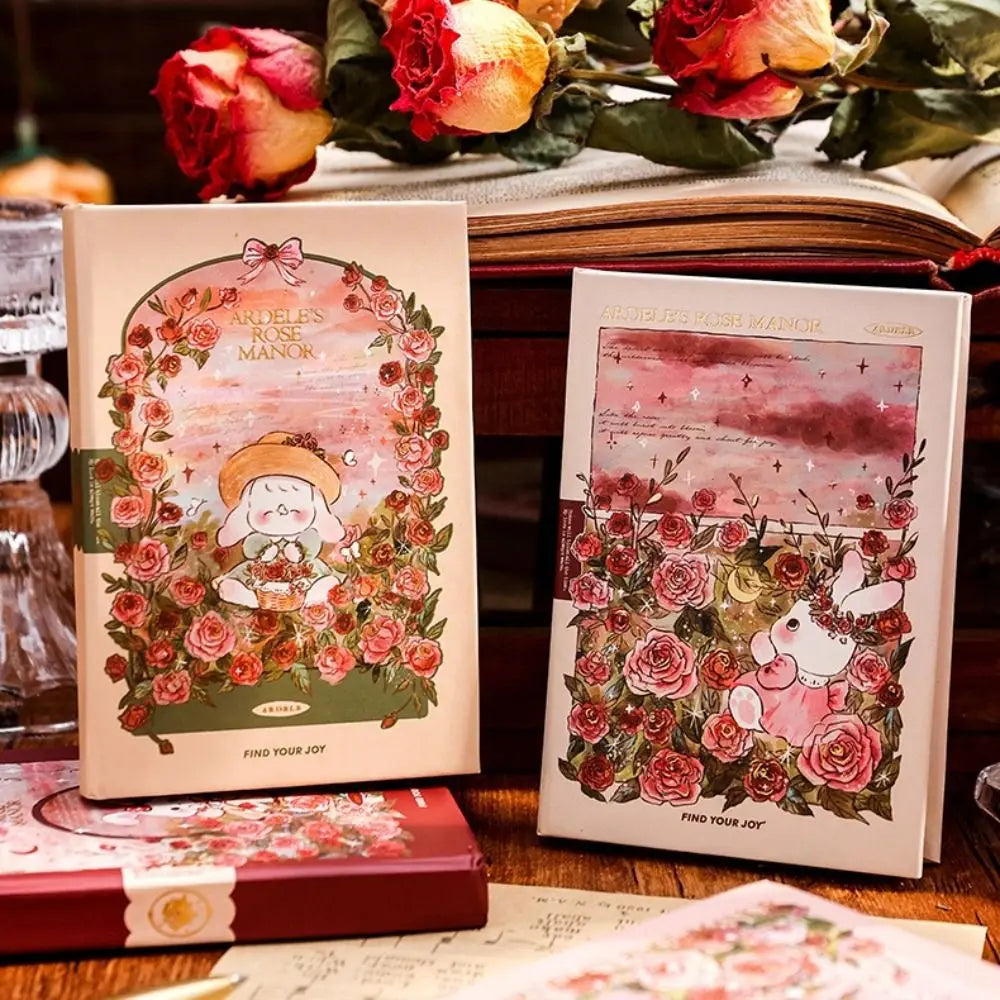 Two illustrated books with floral designs and characters on a wooden surface with flowers in the background.
