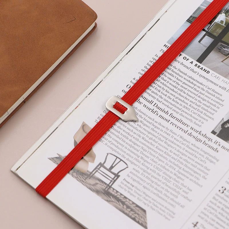 Open book with a red ribbon bookmark on a light pink surface