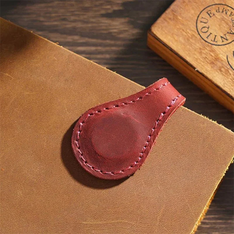 Red leather clip on a brown leather surface with a wooden background