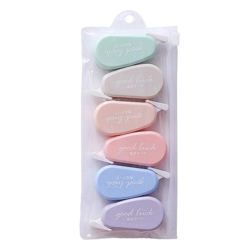Set of pastel-colored erasers with 'good luck' text in a clear package on a white background