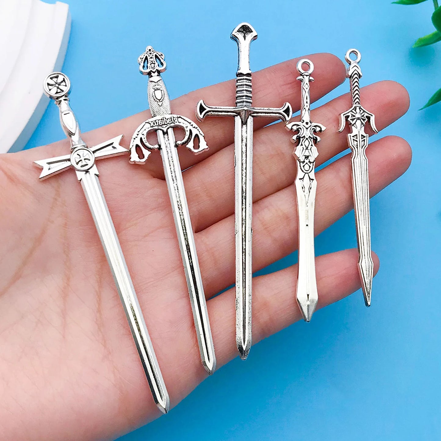 Five silver sword-shaped objects held in a hand against a blue background