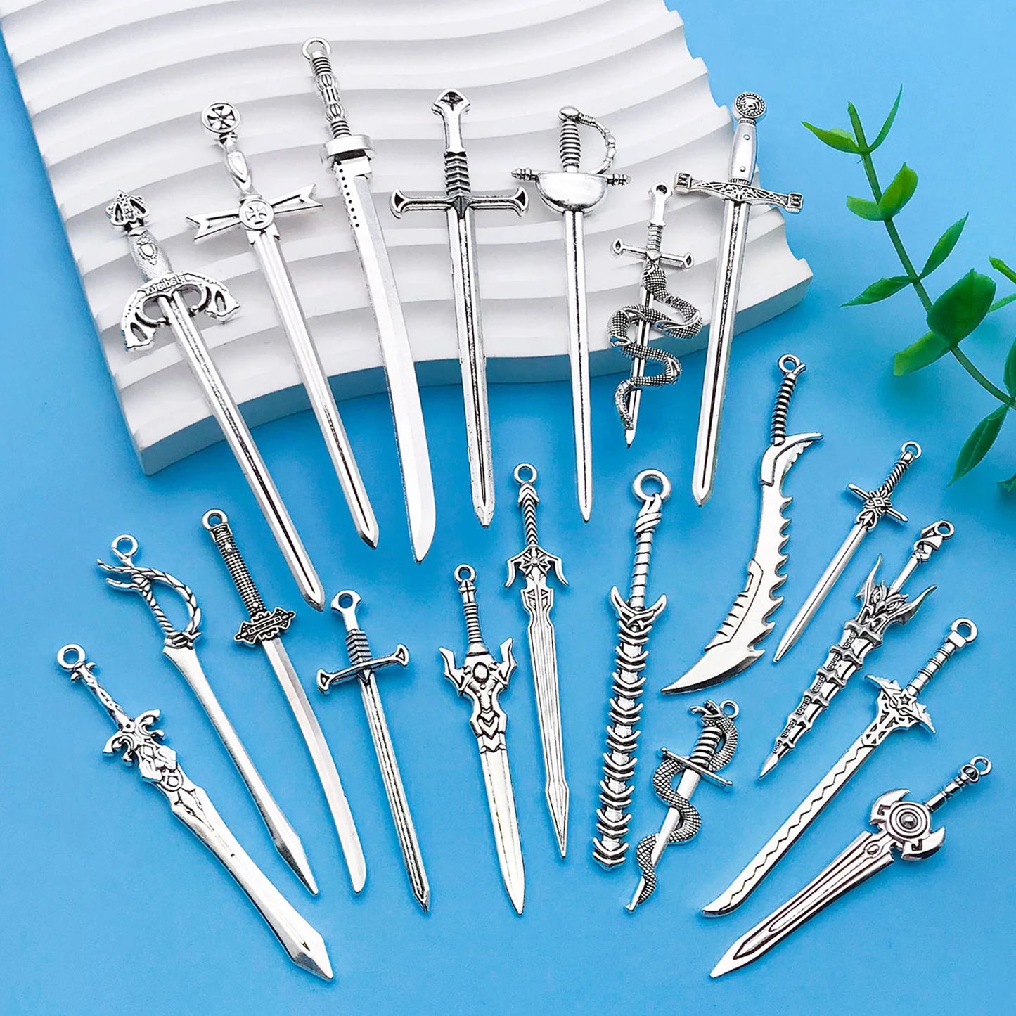 Collection of silver sword-shaped jewelry on a blue background