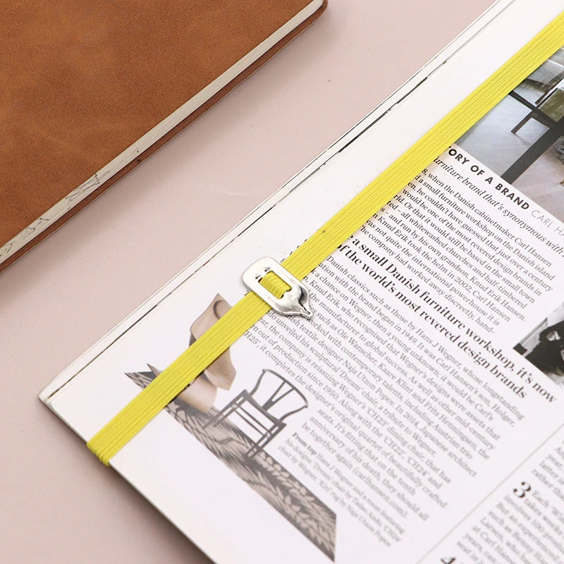 Open magazine with a yellow ribbon bookmark on a pink surface