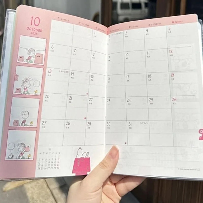Open calendar with a pink border held by a hand, showing October 2023.