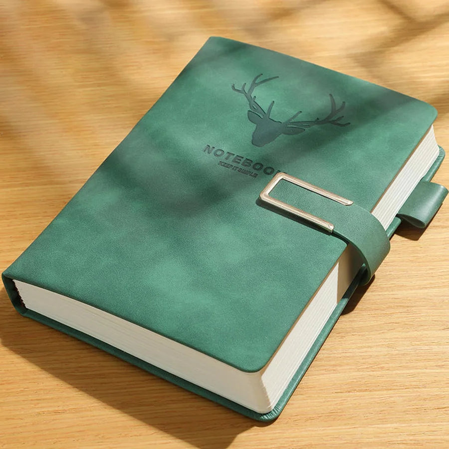 Green notebook with a deer emblem on the cover, placed on a wooden surface.