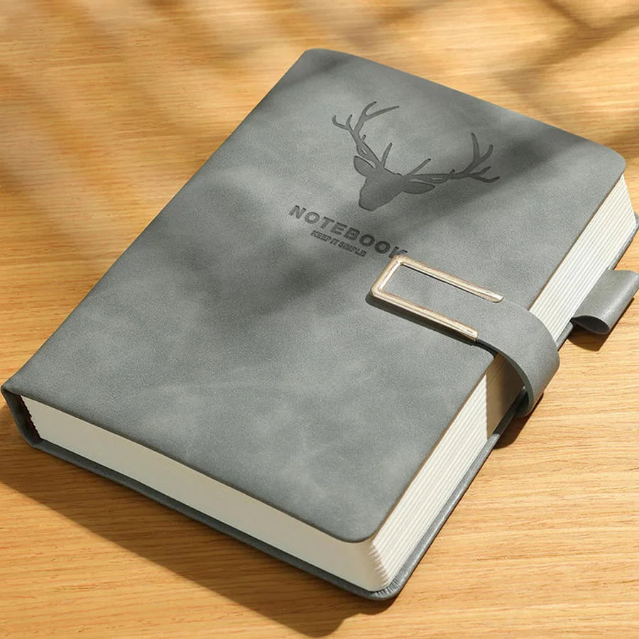 Gray notebook with deer emblem on a wooden surface