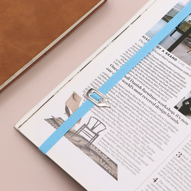Open magazine with a blue ribbon on a beige surface
