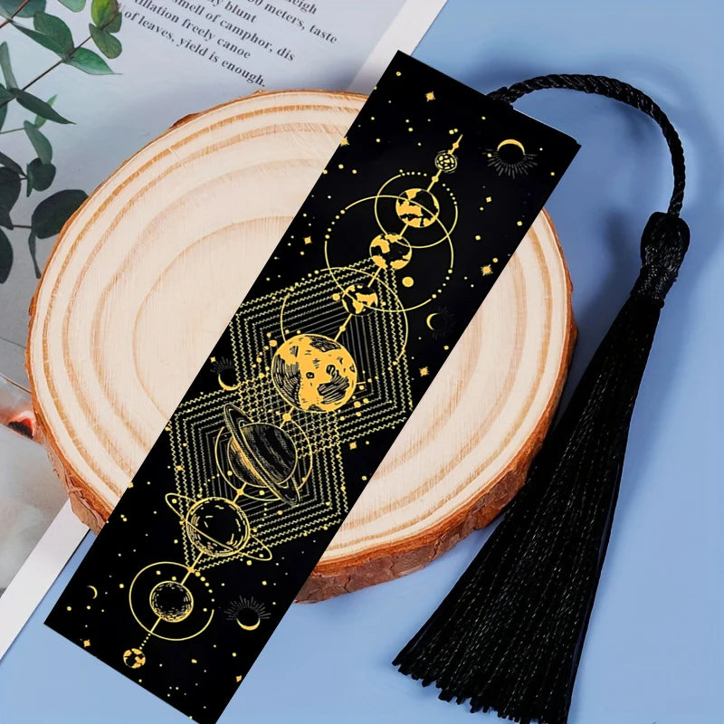 Black bookmark with gold celestial design on a wooden surface
