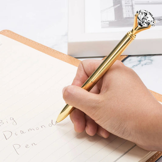 Hand holding a gold pen with a diamond-shaped cap on a notebook.
