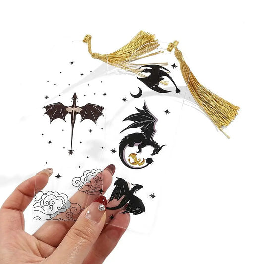 Dragon-themed tassel hair clips with gold tassels held by a hand on a white background