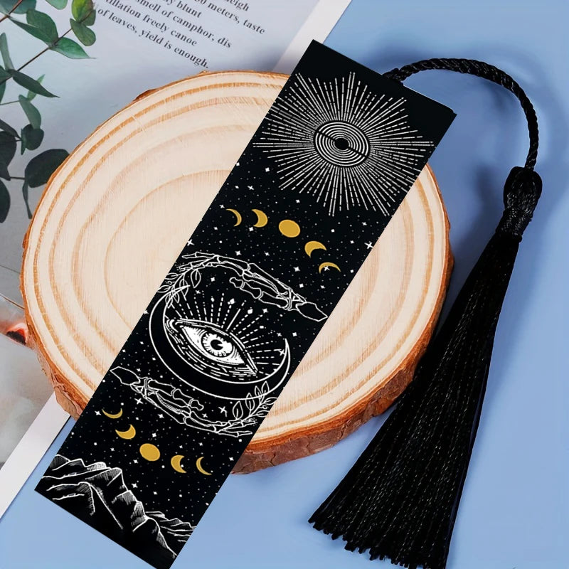 Black and gold celestial bookmark with tassel on a wooden surface