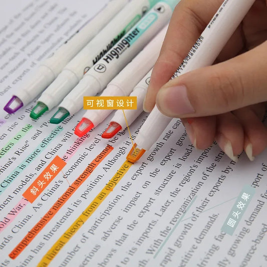 Hand holding a highlighter over text with colorful markers on a book page