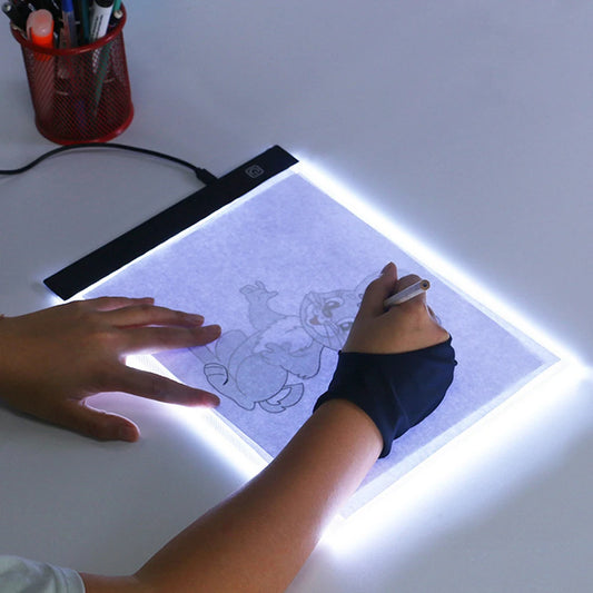 Person using a light pad to draw a cartoon character with a pen.