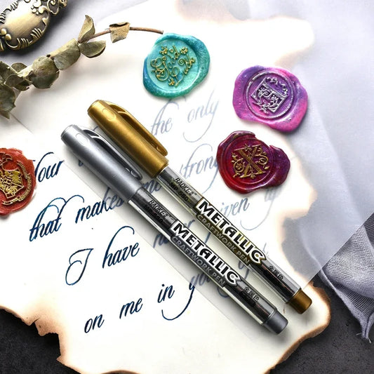 Metallic markers on a surface with decorative wax seals and calligraphy.