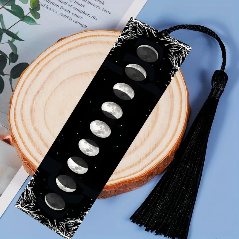 Black bookmark with moon phase design on a wooden surface