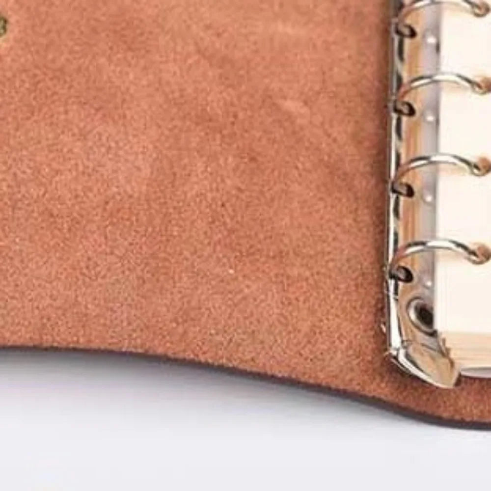 Close-up of a brown leather notebook with a gold metal ring binding on a white background