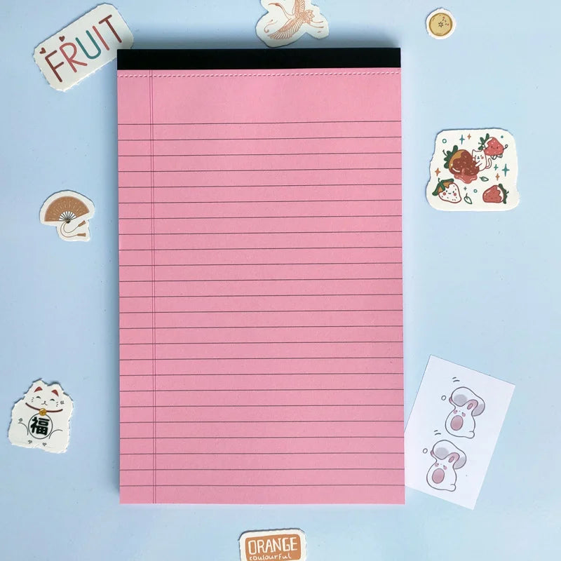 Pink lined notepad with decorative stickers on a light blue background