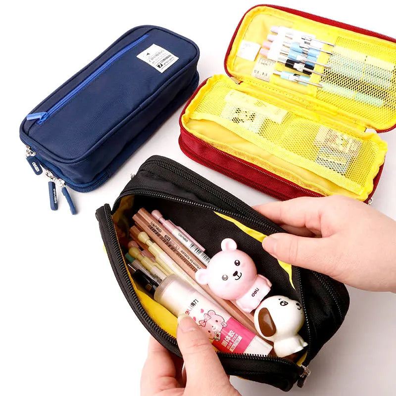 Pencil case with stationery items including pens and a small bear-shaped container, held by a hand.
