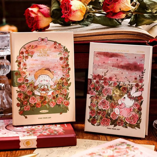 Two illustrated books with floral designs and characters on a wooden surface with flowers in the background.