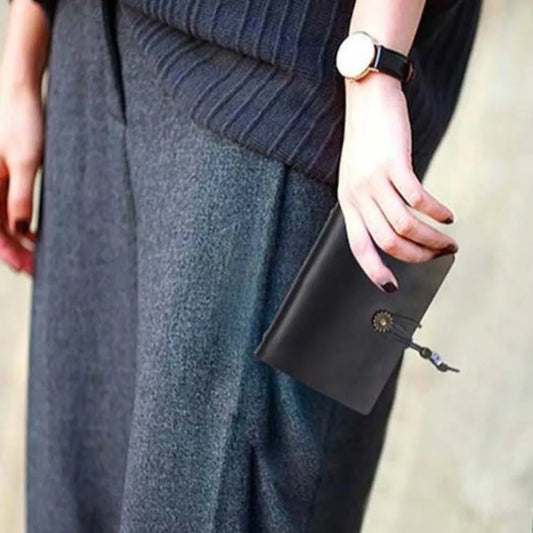 Person holding a black wallet with a blurred background