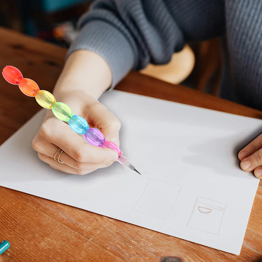 Person holding a colorful pen over a piece of paper on a wooden table.