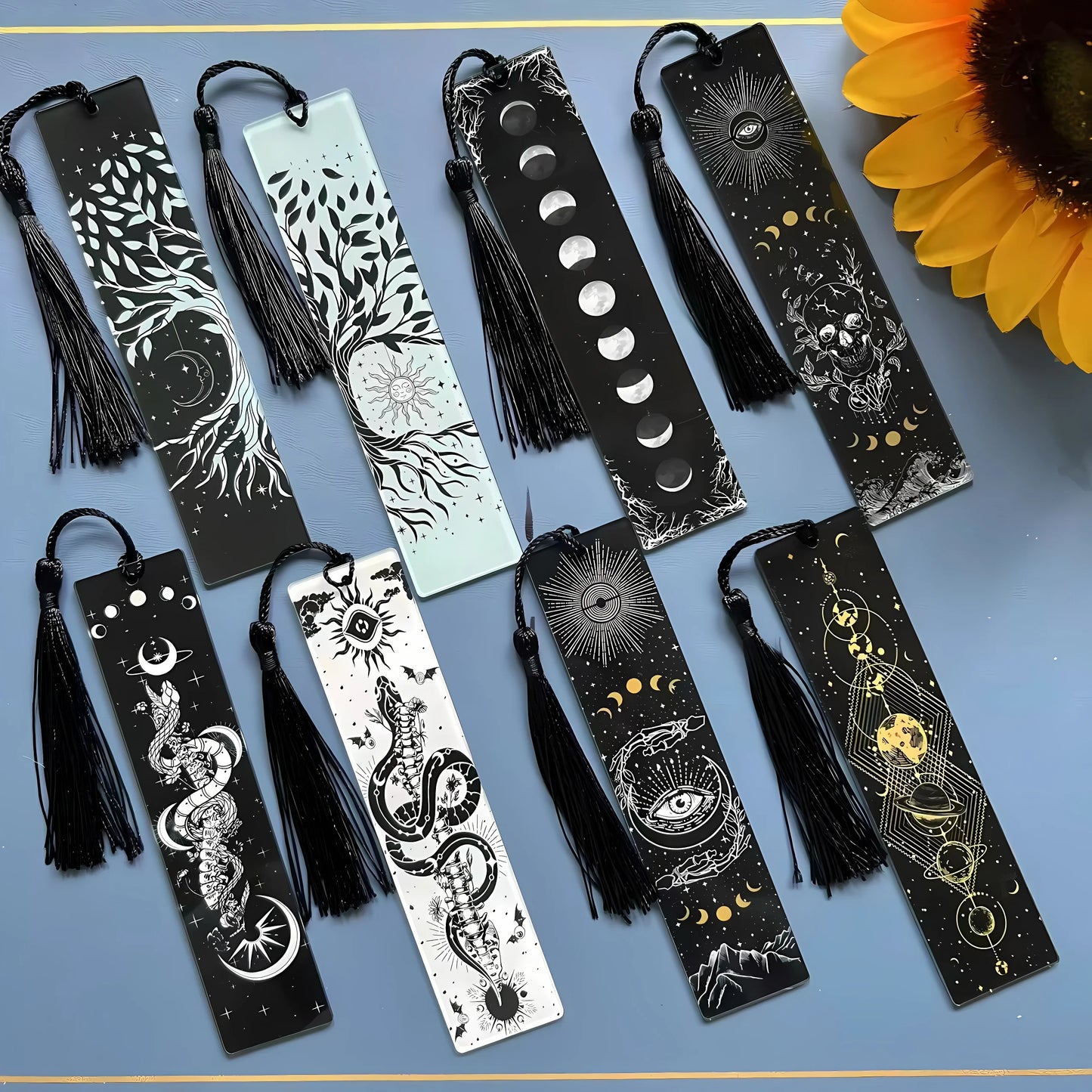 Set of black bookmarks with tassels and intricate designs on a blue background.