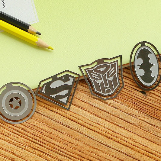 A collection of metal bookmarks with superhero designs including a batman logo, a superman logo, and other comic book characters.