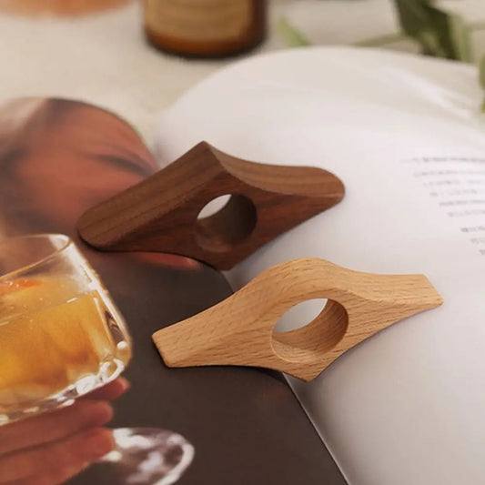 Two wooden bottle openers on a magazine with a glass of orange juice in the foreground.